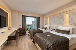 a hotel room with two beds and a desk at Limak Eurasia Luxury Hotel in Istanbul