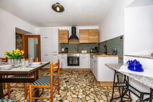 een keuken met witte kasten en een tafel en stoelen bij MICIKA Country house in Grižane