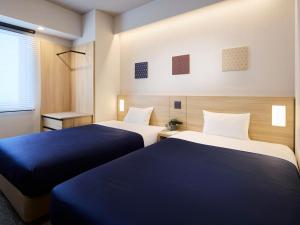 Dos camas en una habitación con azul y blanco. en Minn Ueno Shin-Okachimachi, en Tokio