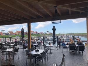 people sitting at tables on a deck with a marina at Vakantiehuis in Stavenisse