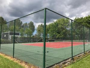 a fence on a tennis court with two tennis courts at Vakantiehuis in Stavenisse