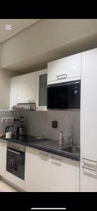 Una cocina con gabinetes blancos y un fregadero. en منتجع هوانا صلاله, en Salalah