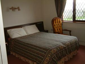 a bedroom with a bed and a chair and a window at Seanor House Bed & Breakfast in Ballybunion