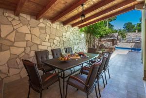 a patio with a table and chairs and a stone wall at MSV Modern Stone Villa in Imotski