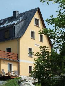 a house with a black roof and chairs on a balcony at Ferienwohnung In Bad Elster Mit Grill, Terrasse Und Garten in Bad Elster