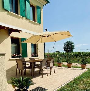 a patio with a table and chairs and an umbrella at Casa Cabini Piave in Eraclea