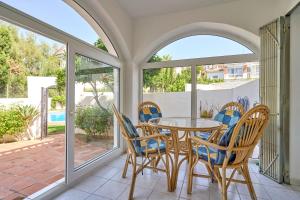 Un comedor con mesa y sillas y ventanas. en Casa Alina, en Nerja