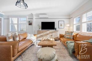 a living room with brown leather furniture and a flat screen tv at Journeyman's Cottage in Ballarat