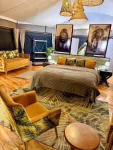 ein Schlafzimmer mit einem Bett, einer Couch und einem Sessel in der Unterkunft Olkinyei Mara Tented Camp in Talek