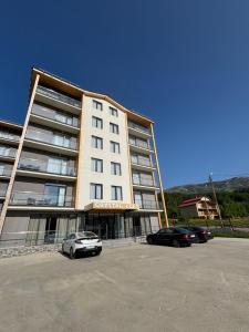 un grande edificio con auto parcheggiate in un parcheggio di Crystal Loft a Bakuriani