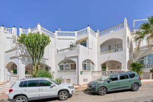 dos autos estacionados frente a un edificio blanco en Casa Alina, en Nerja