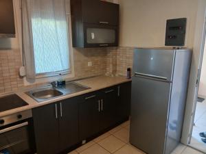 a kitchen with a stainless steel refrigerator and a sink at Blue Sky Apartment in Chrysi Ammoudia