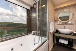 a bathroom with a tub and a sink and a window at Limak Eurasia Luxury Hotel in Istanbul