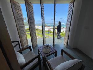 a person standing in a balcony looking out at the ocean at Marshmallow Bay Boutique Hotel & Surf Point Adults Only in Ahangama