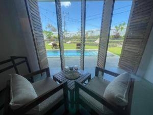 a room with two chairs and a table with a view of a pool at Marshmallow Bay Boutique Hotel & Surf Point Adults Only in Ahangama