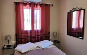a bedroom with a bed with red curtains and a window at Dimitras house palaiopoli in Kythira