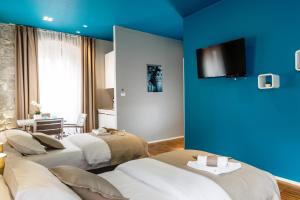 two beds in a room with a blue wall at Riva Luxury Rooms in Split