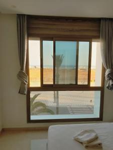 een slaapkamer met een raam met uitzicht op de woestijn bij Appartement vue sur mer, terrasse ensoleillée in Asilah
