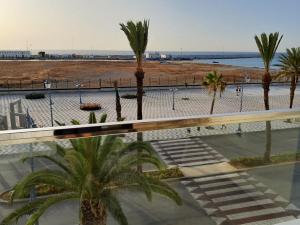 een balkon met palmbomen en uitzicht op het strand bij Appartement vue sur mer, terrasse ensoleillée in Asilah