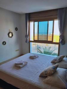 een slaapkamer met een groot bed met een groot raam bij Appartement vue sur mer, terrasse ensoleillée in Asilah