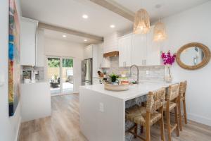 una cocina con armarios blancos y una isla de cocina con sillas en Sun Seekers Beach House- Steps from Butler Beach, en St. Augustine
