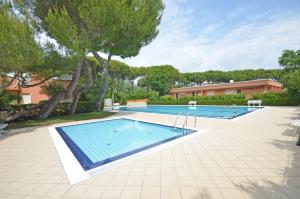 a swimming pool in a yard with trees and a building at Residence Garuda in Cavallino-Treporti