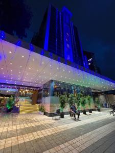 un hombre sentado en un banco frente a un edificio en Hotel Sahar Garden Near Mumbai International Airport, en Bombay