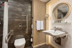 a bathroom with a sink and a toilet and a mirror at Limak Eurasia Luxury Hotel in Istanbul