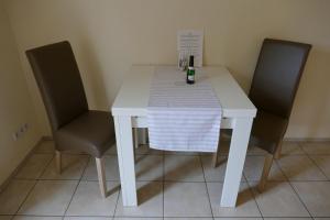 une table blanche avec deux chaises et une bouteille de vin dans l'établissement Ferienhaus Frida, à Samtens