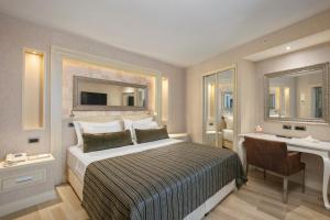a bedroom with a bed and a desk and a mirror at Limak Eurasia Luxury Hotel in Istanbul