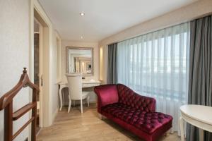 a living room with a red chair and a desk at Limak Eurasia Luxury Hotel in Istanbul