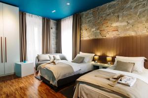 a hotel room with two beds and a brick wall at Riva Luxury Rooms in Split