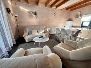 a living room with couches and a table and a kitchen at Domki Kalipso in Sarbinowo