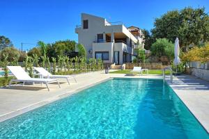 a swimming pool with chairs and a house at Dioni by PosarelliVillas in Kounoupidhianá