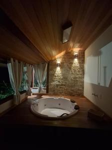 a large bath tub in a room with a stone wall at Chalé Canarinho in São Pedro da Serra +18 photos