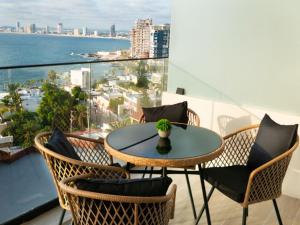 マサトランにあるSunset Mazatlán • Rooftop Pool Breathtaking Viewの海が見えるバルコニーにテーブルと椅子がある