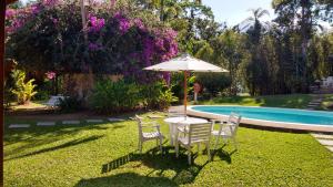 a table and chairs with an umbrella next to a pool at Pousada Penedo in Penedo