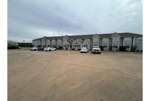 a large building with cars parked in a parking lot at Motel 6 Idabel, OK in Idabel