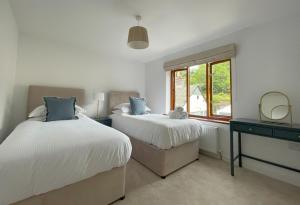 two beds in a bedroom with a mirror and a window at Mill House in Braithwaite
