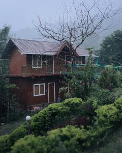 una casa rossa con balcone e cortile di Don's River Valley Jungle Resort a Maraiyūr
