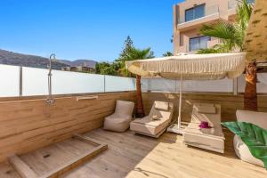a patio with an umbrella and chairs on a balcony at Villa Karteris by Villa Plus in Stalida