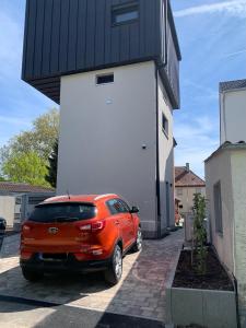 une voiture orange garée devant un bâtiment dans l'établissement Turmquartier Weinsberg, à Weinsberg