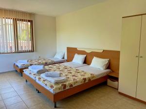 Un dormitorio con dos camas y una ventana. en Къща за Гости Чайка, en Byala