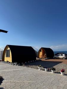 a group of tents in a parking lot with a car at Tasmal Yurt Camp in Tong