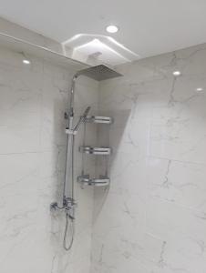 y baño con ducha y paredes de mármol blanco. en appartement marina bay, en Tánger