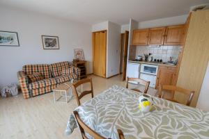 a kitchen and a living room with a table and a couch at Au Coin des Souvenirs in Malbuisson