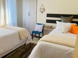 a bedroom with two beds and a chair at Tsika's Inn in Gaborone