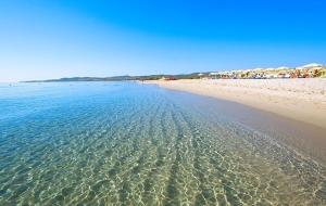 a beach with clear water and houses in the background at Gió guest house in La Caletta +28 photos