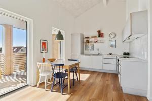 a kitchen with white cabinets and a table and chairs at Feriehus 1135 in Ringkøbing