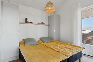 a bedroom with a bed with a yellow blanket at Feriehus 1135 in Ringkøbing